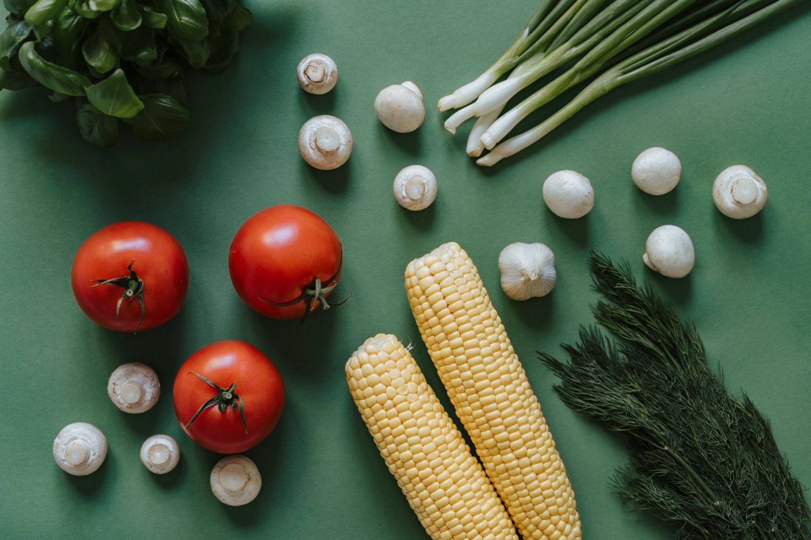 Fresh vegetables arranged on a green background, seen from above